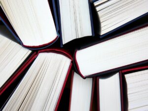 Closeup photo of hardcover books that are standing up straight. You can see glimpses of their red or blue covers and then nothing else except their pages, some of which have begun to gently fan out. 